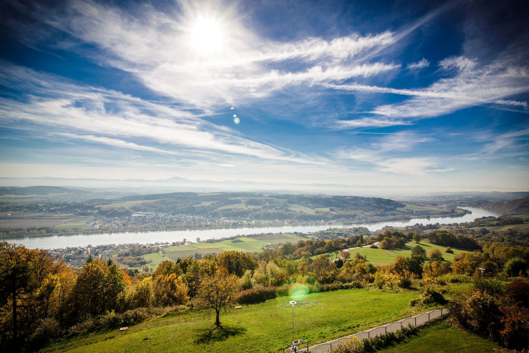 Panoramic view of a river landscape with green fields and blue sky.