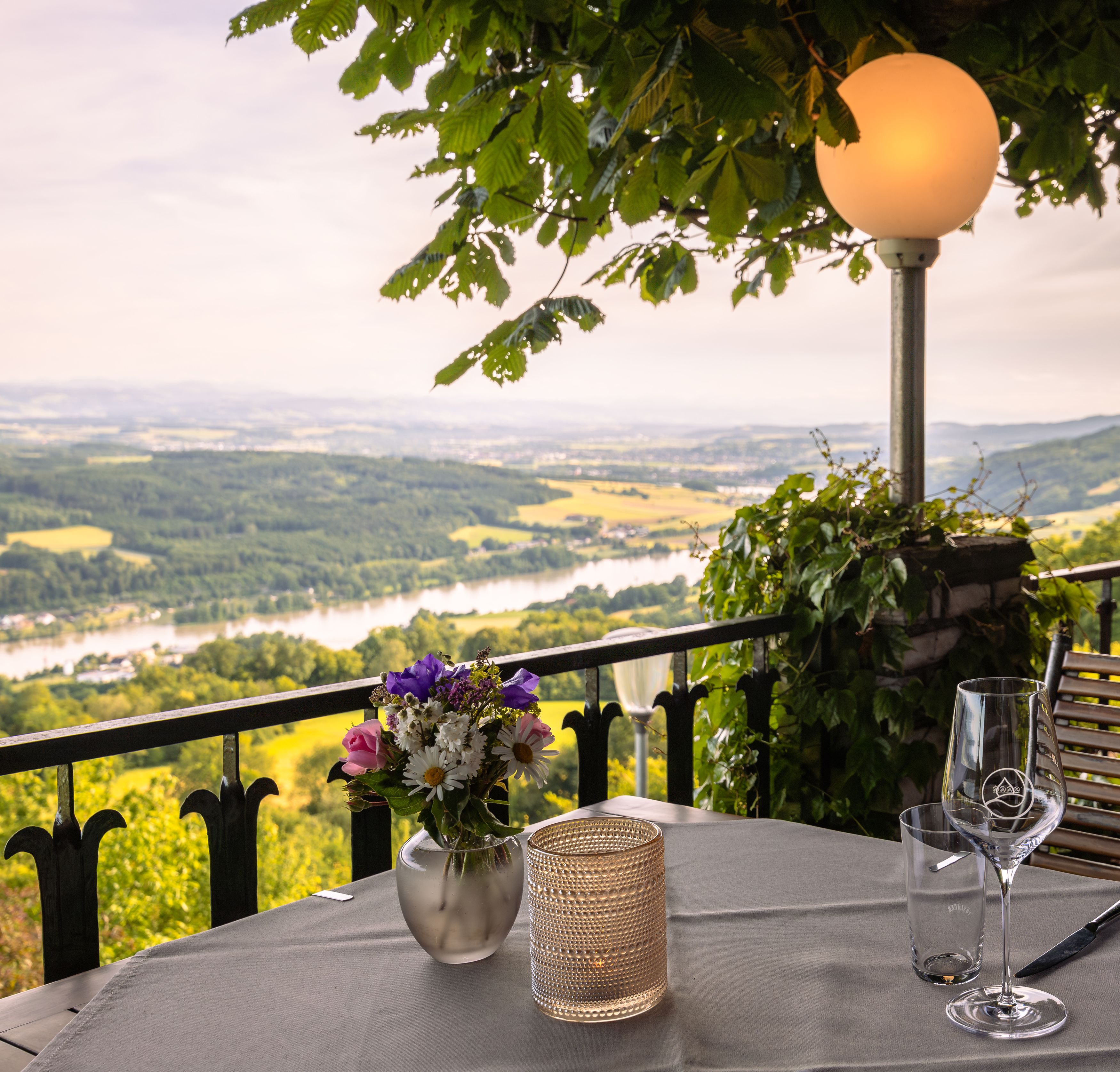 Terrace with table, flowers and view of the river landscape.
