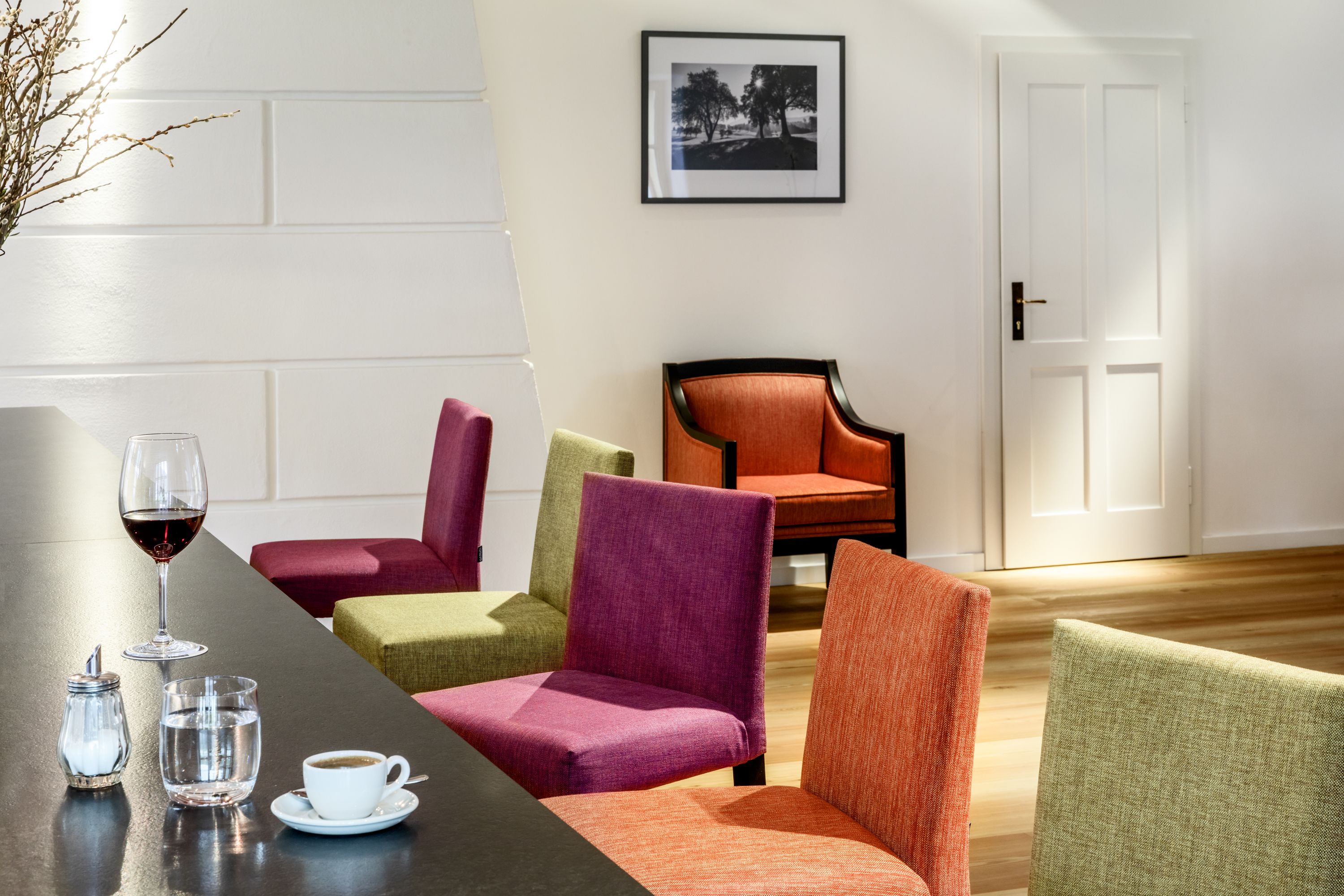Interior view of a modern hotel lounge with colorful chairs, a table with drinks and a picture on the wall.