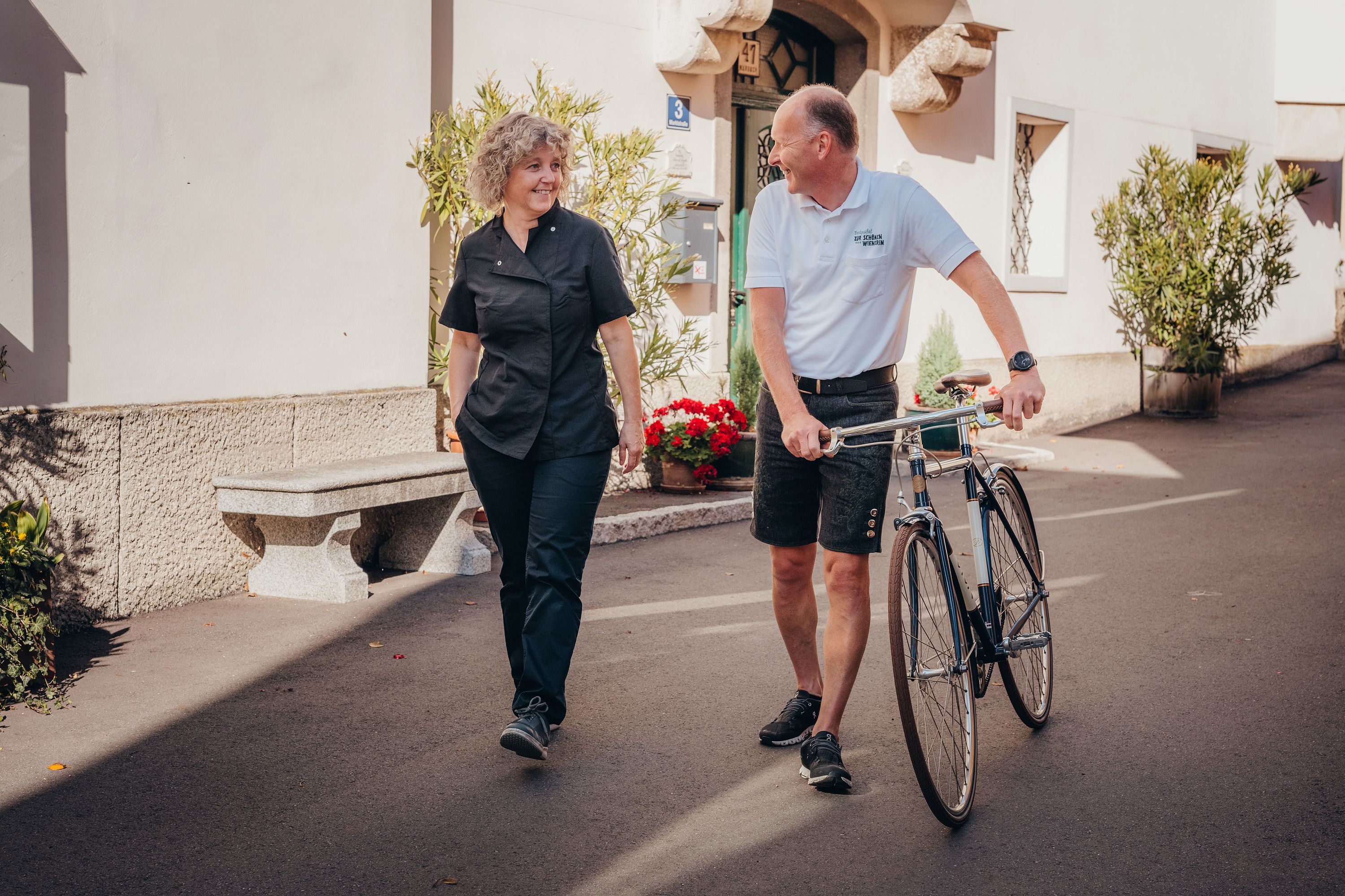 Two people are talking while one pushes a bicycle.