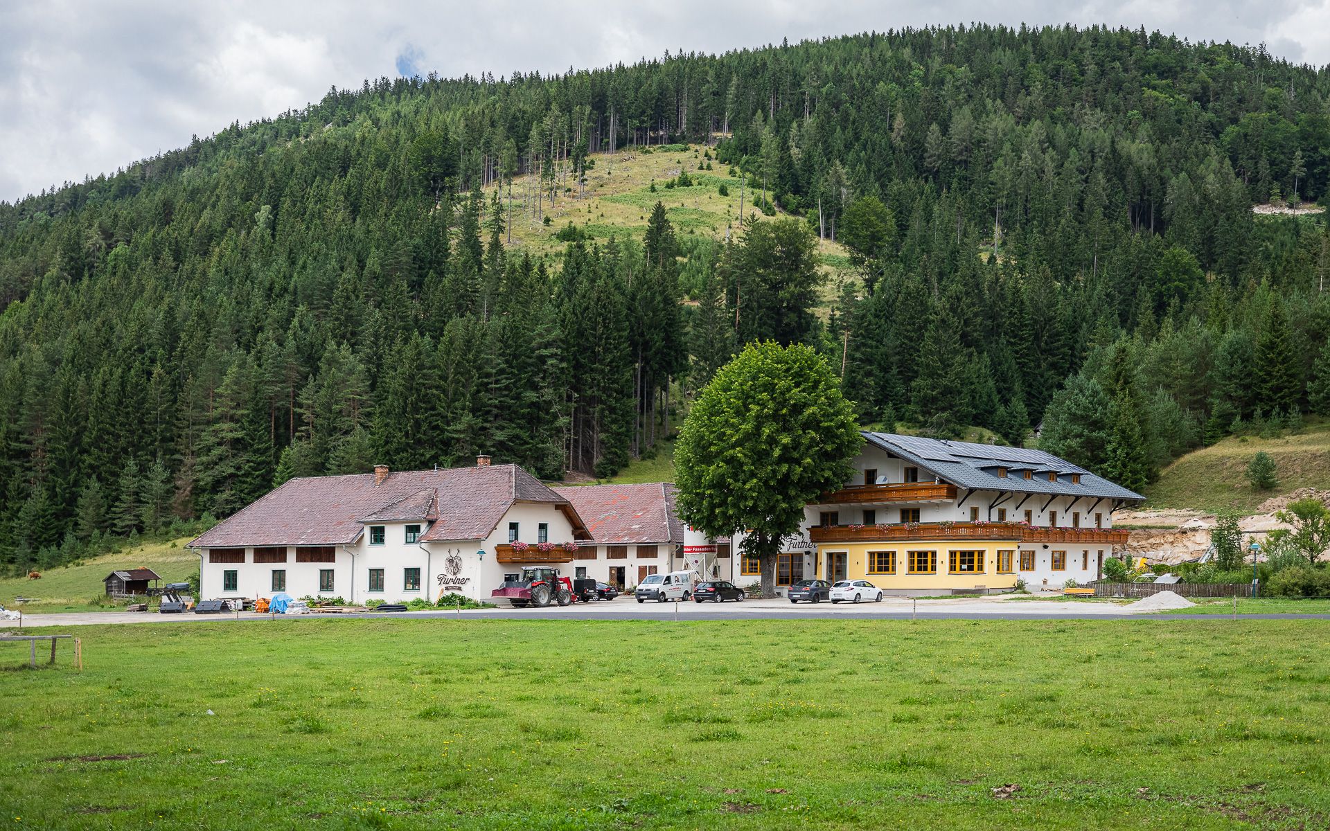 Gasthof Furtner in front of a wooded hill.