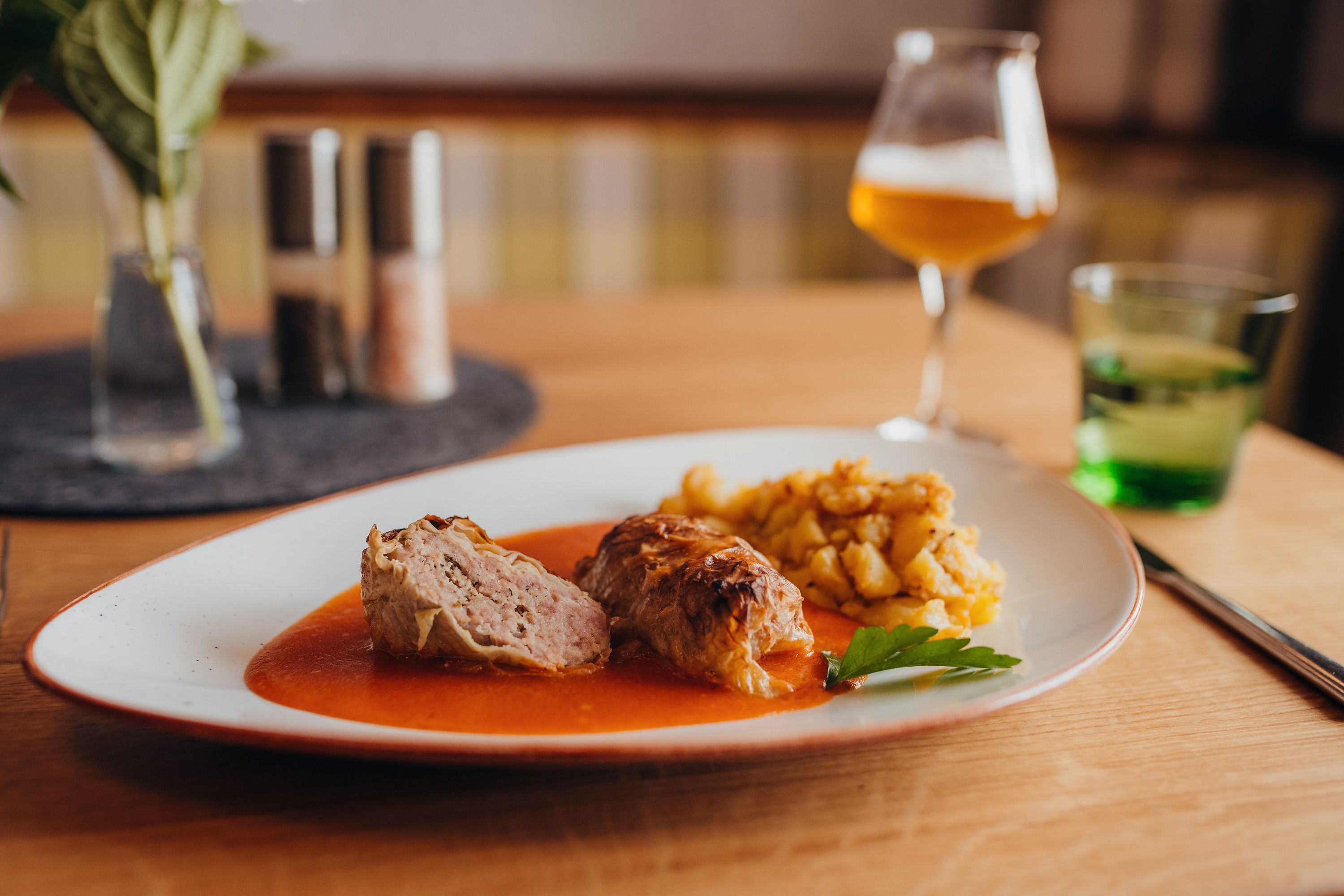 Cabbage roulade with sauce and potato garnish served on a plate.