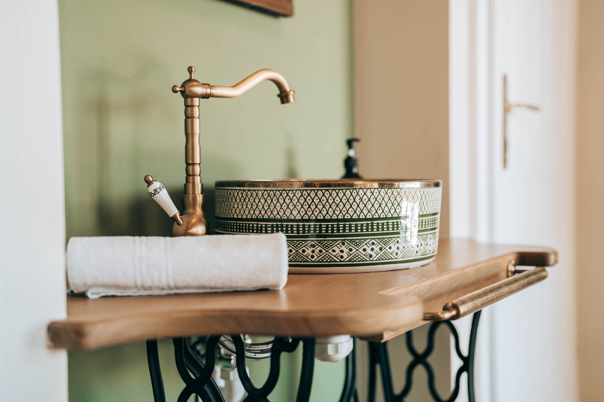A stylish bathroom with a decorative washbasin and a golden tap on a wooden washstand.
