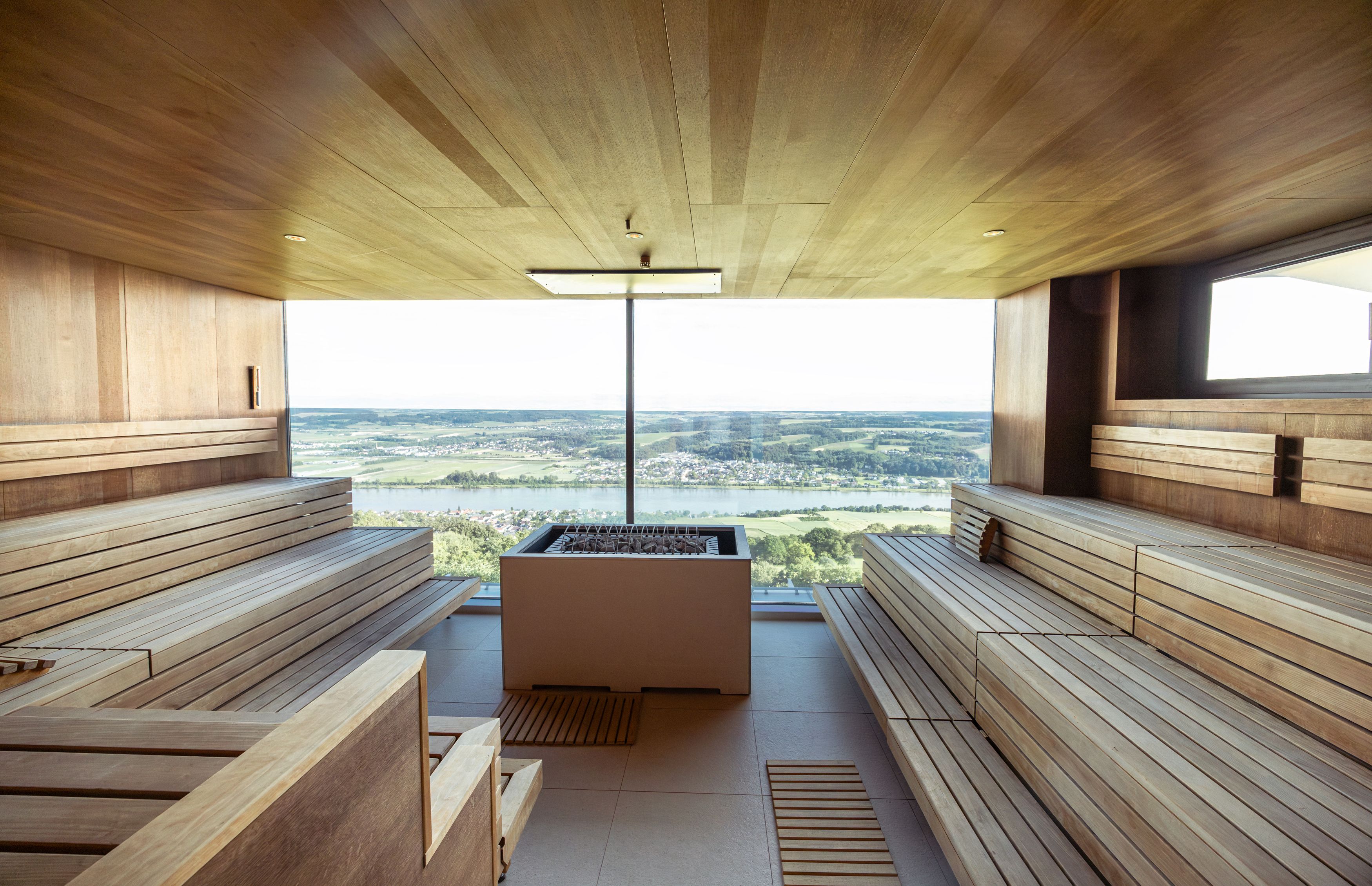 Interior view of a sauna with a panoramic view of a landscape.