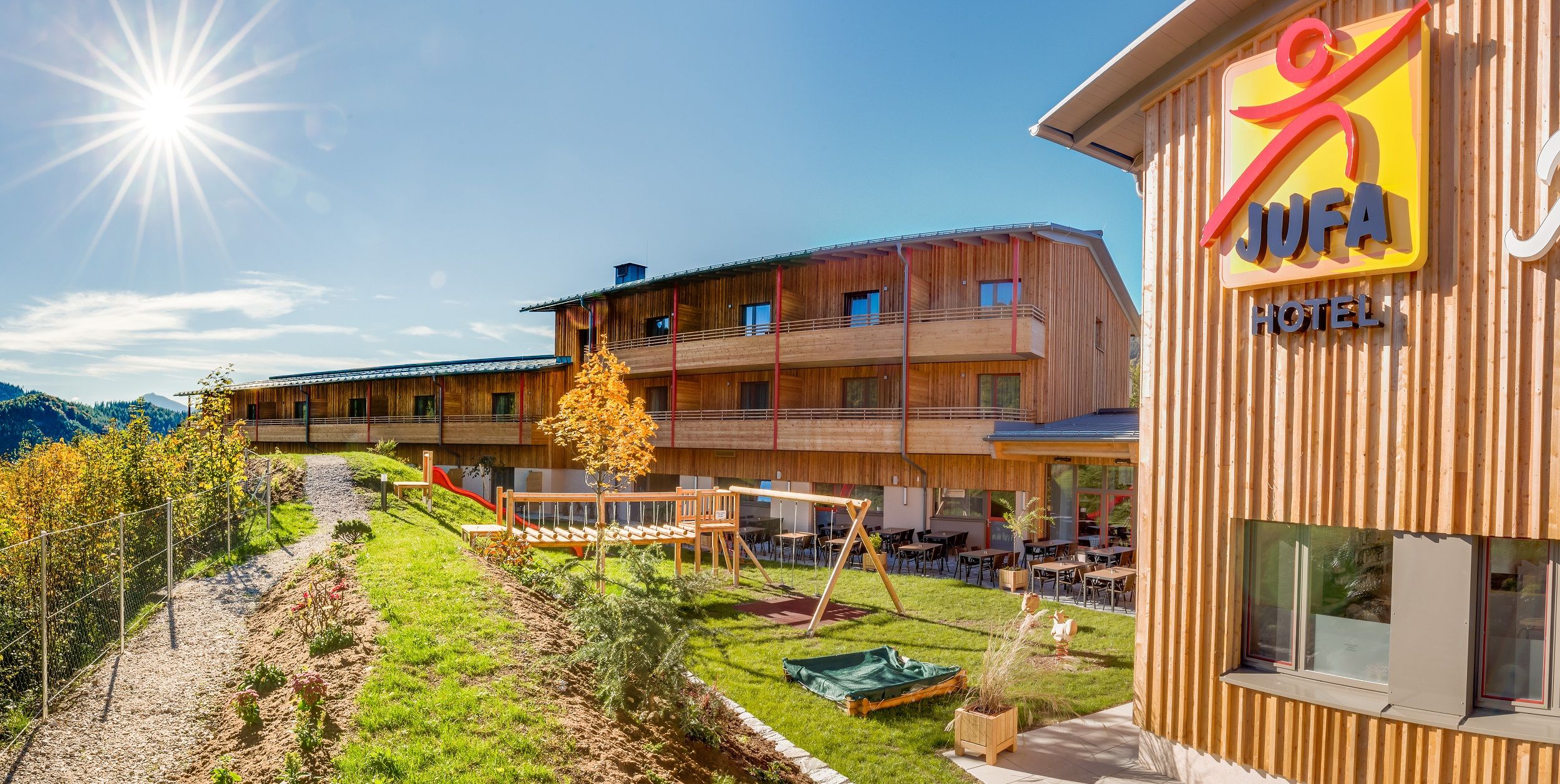 JUFA Hotel Annaberg with playground and sunny sky.