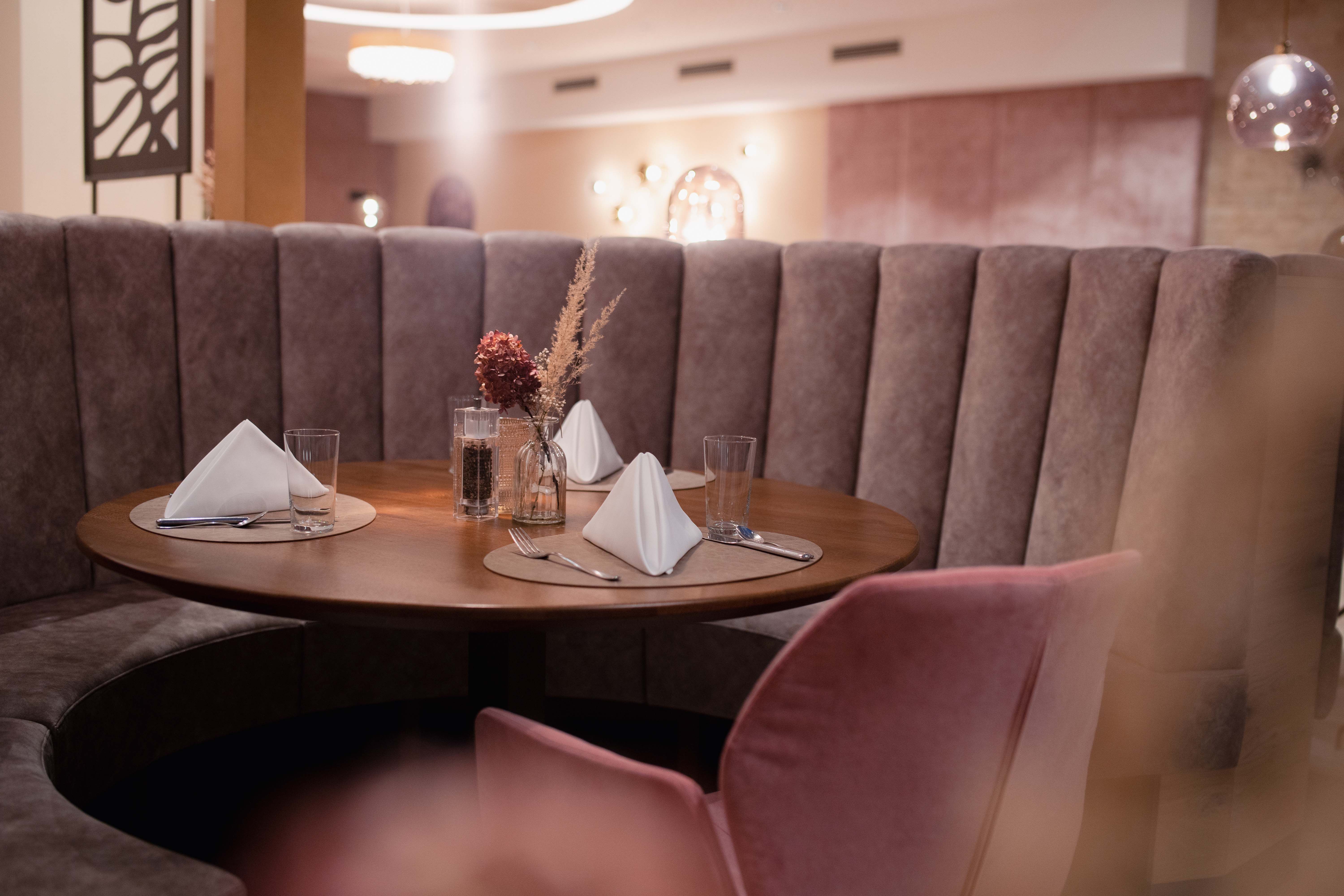 Elegant restaurant with round bench and table setting.