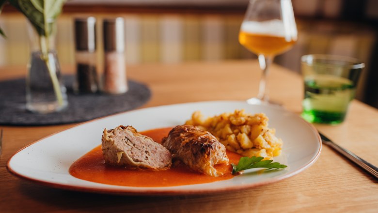 Cabbage roulade with sauce and potato garnish served on a plate.