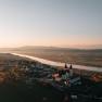 Aerial view of a church at sunset, surrounded by river and landscape.