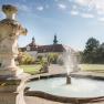 Fountain in the garden of Seitenstetten Abbey with baroque architecture in the background.