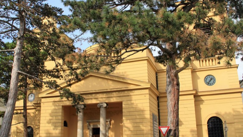Exterior view of the Hinterbr&uuml;hl parish with yellow fa&ccedil;ade and clock.