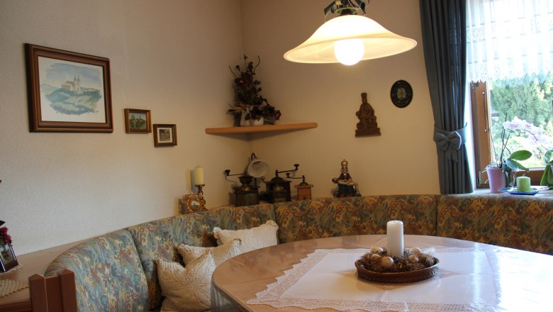 Cozy breakfast room with corner bench, table, candle and decorations on the wall.