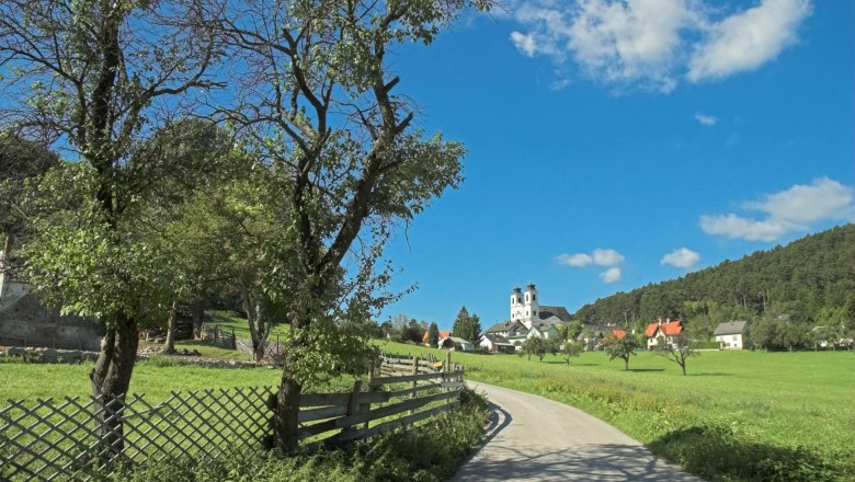 Landscape with church and trees under a blue sky.
