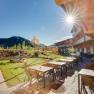 Terrace of the JUFA Hotel Annaberg with tables, chairs and playground in the background in the sunshine.