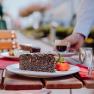 Poppy seed cake with strawberry and espresso served on a wooden table outside.
