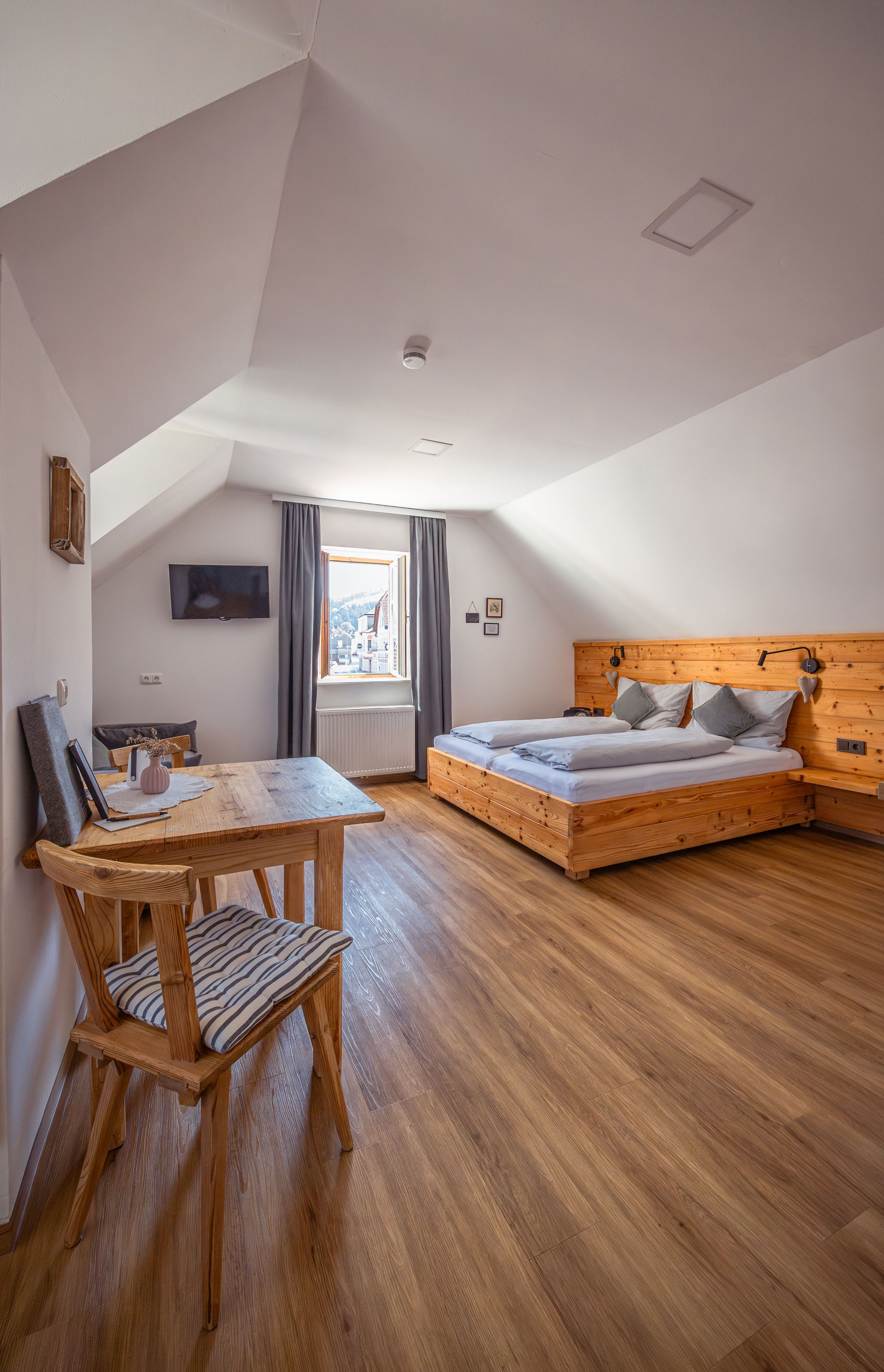 Cozy bedroom with wooden furniture and sloping ceiling.
