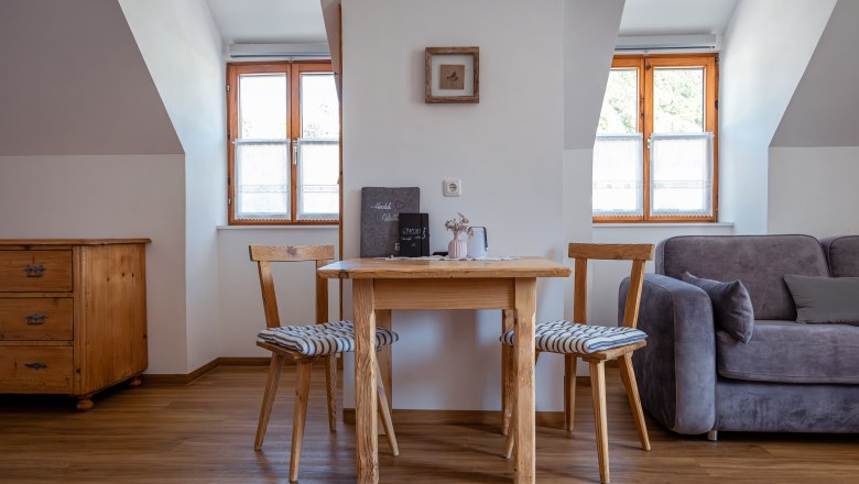 Cozy living area with wooden table, two chairs and sofa.