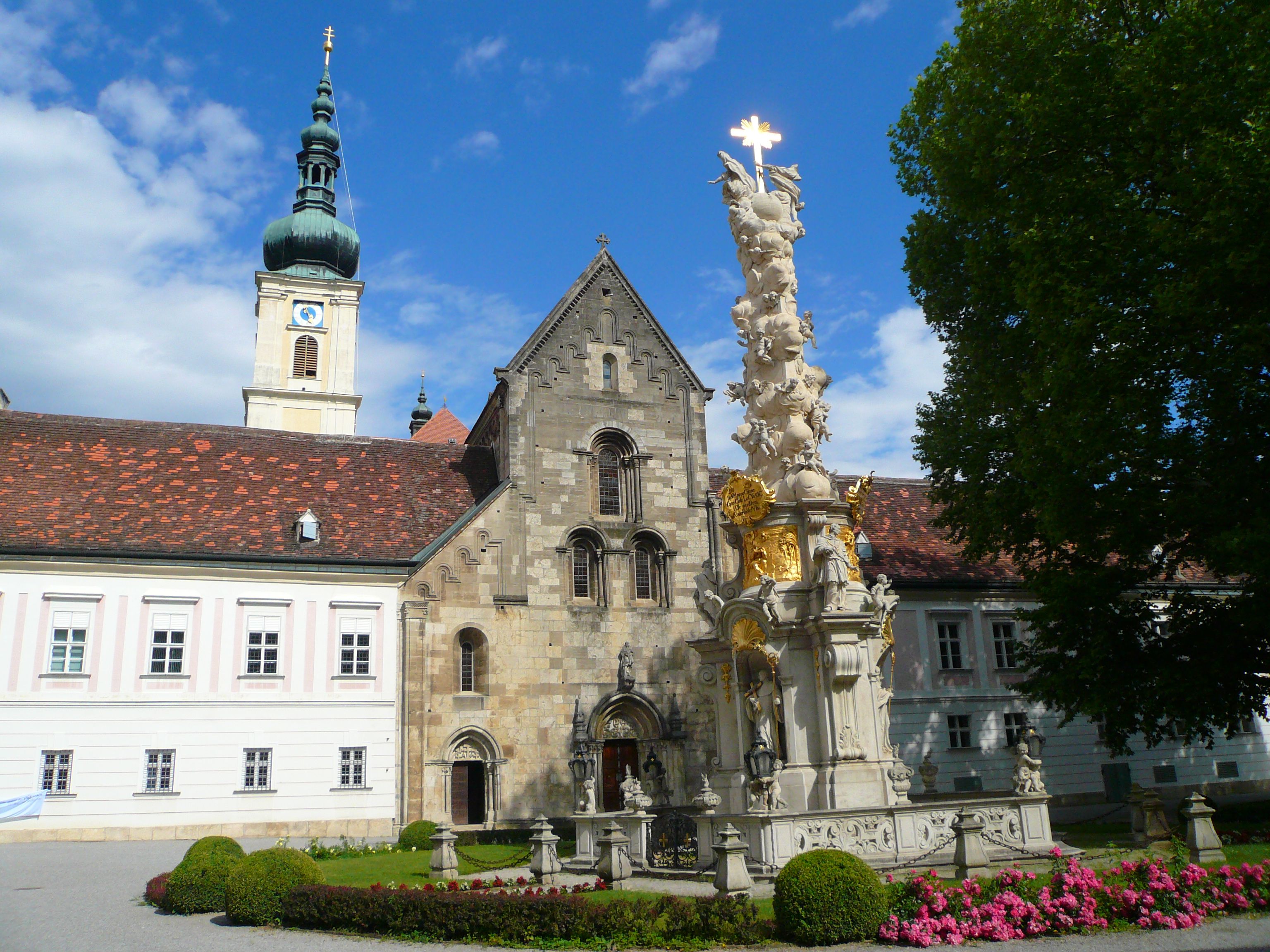 Inner courtyard of Heiligenkreuz Abbey with baroque column and church tower.