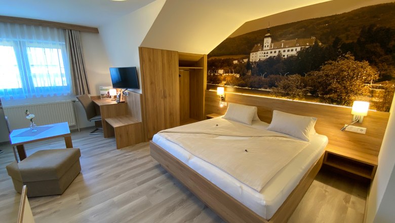 Modern hotel room with double bed, desk, TV and large mural.