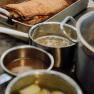 Roast in a casserole dish with pots on a stove in the kitchen.