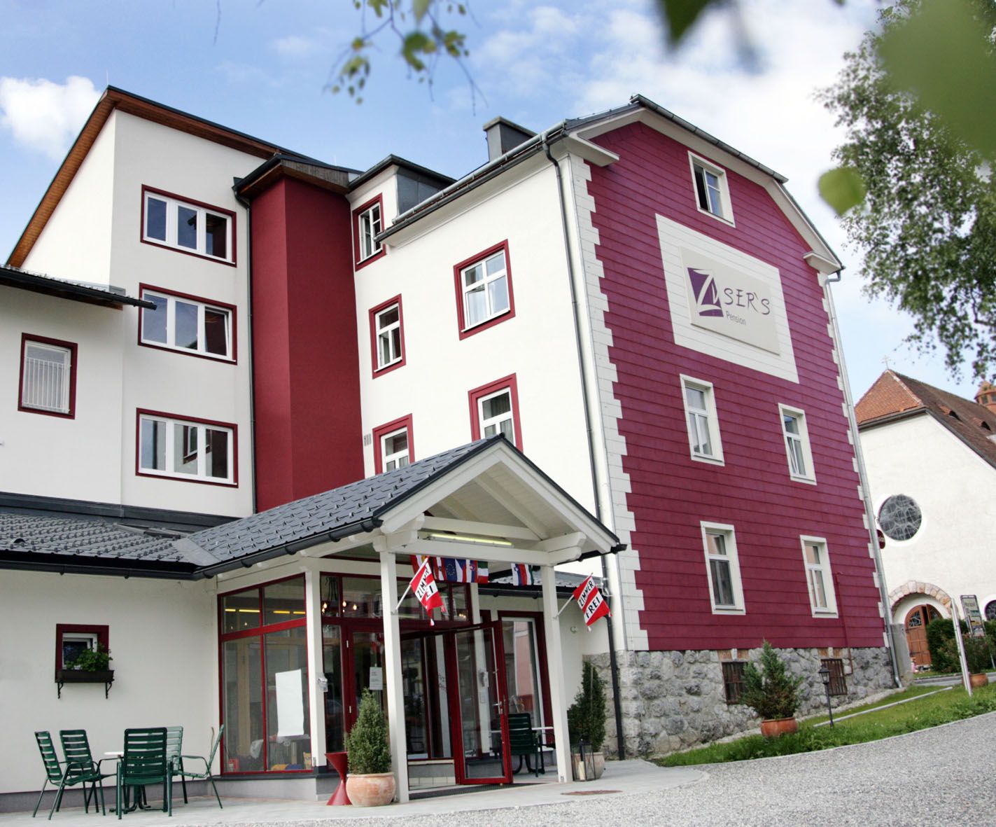 Exterior view of a multi-storey building with a red and white façade, labeled "Zusers Pension".