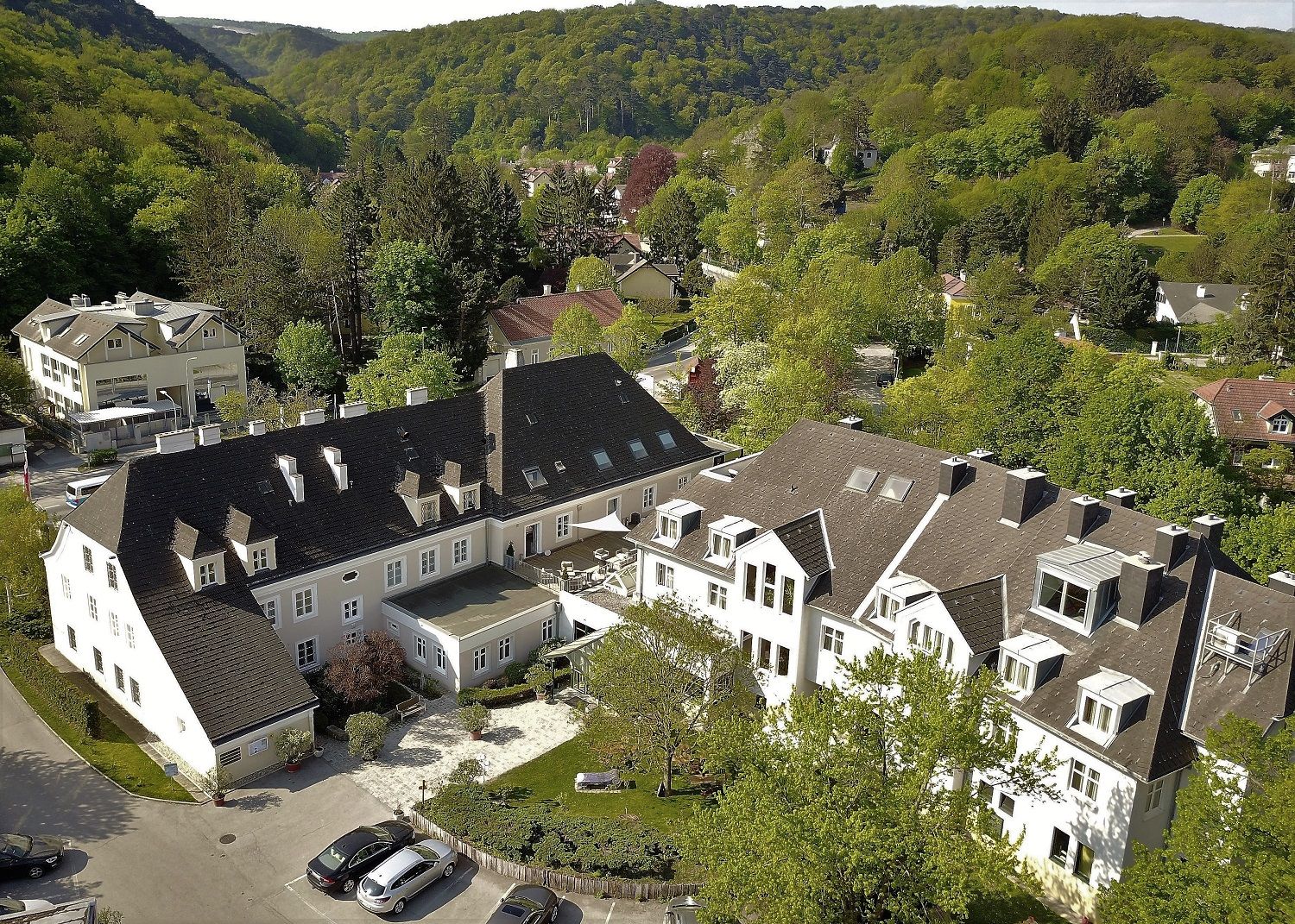 Aerial view of a large building complex surrounded by green trees and hills.