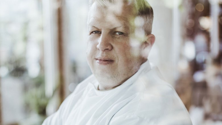 Portrait of a man in a white shirt, photographed through a window.