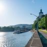 River with ship and building on the bank, sunny sky.
