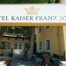 Entrance to the Hotel Kaiser Franz Josef with sign and trees.