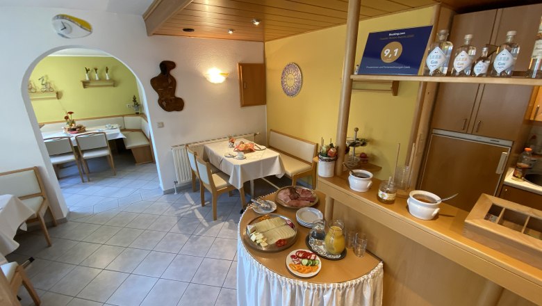 Breakfast room with laid tables and breakfast buffet.