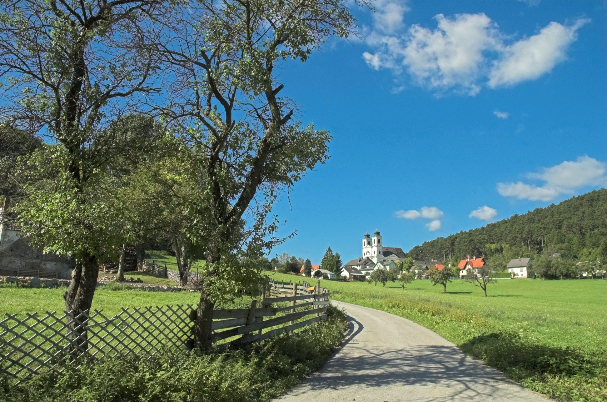 Landscape with church and trees under a blue sky.