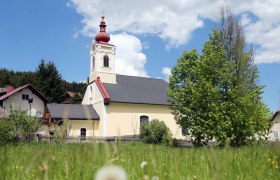 Church in Mitterbach with red tower and green tree in the foreground.