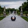 A gravel path in the historic courtyard garden of Seitenstetten Abbey with sculptures and plants, a fireplace in the foreground.