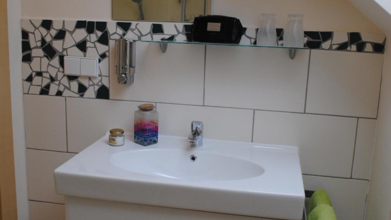 Modern bathroom with washbasin, mirror and mosaic tiles.