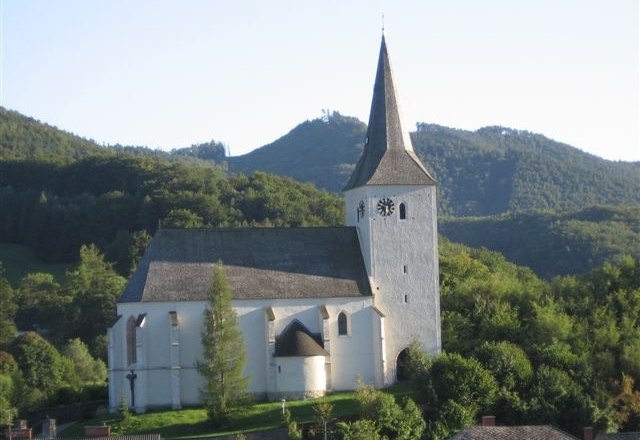 Kaumberg parish church in front of wooded hills.