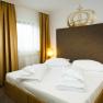 A double room with a large bed, golden curtains and two bedside tables with lamps.