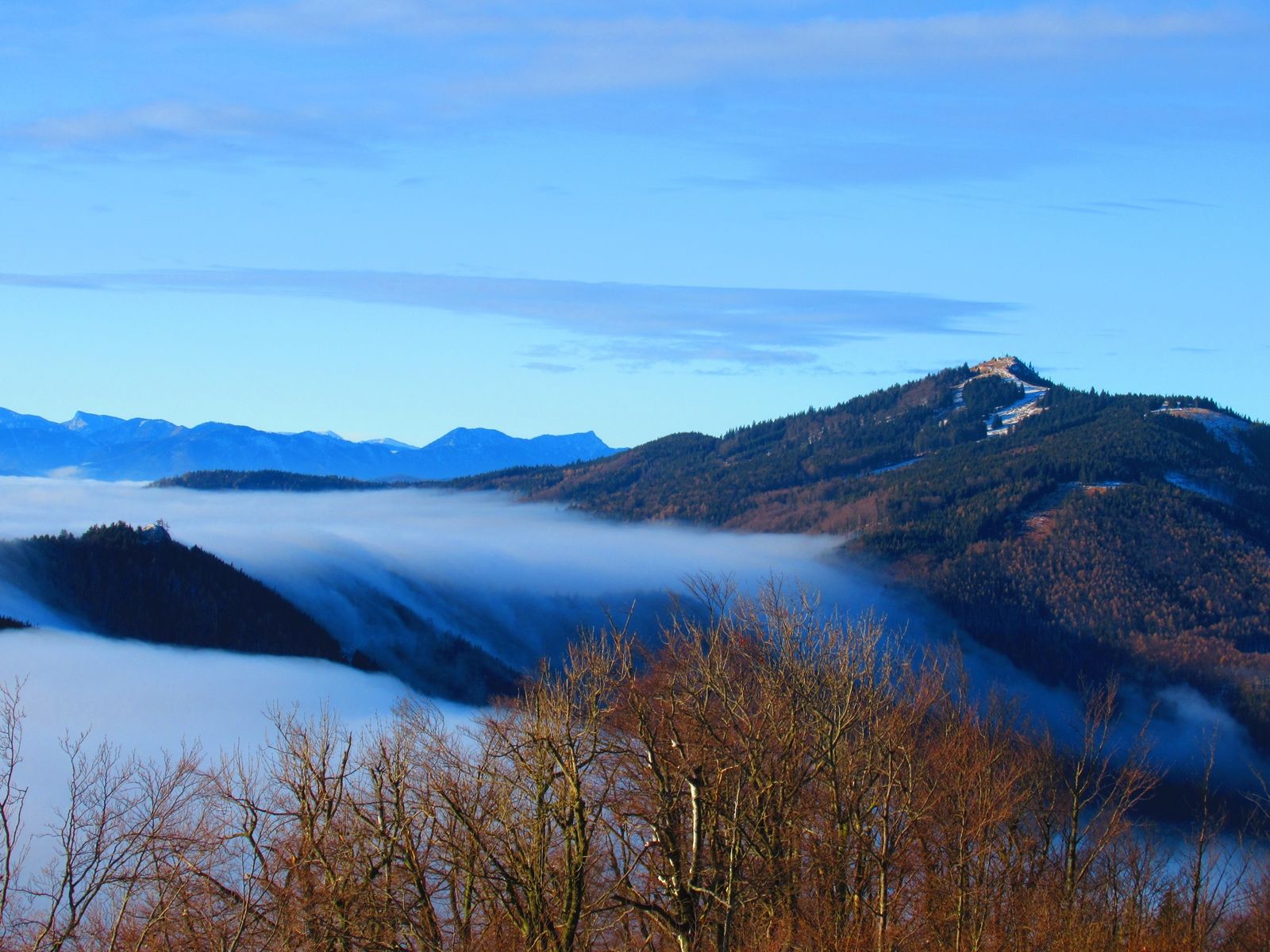 View from a mountain of mist-covered valleys and wooded hills.
