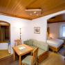 Comfortable hotel room with wooden furniture, dining table, sofa and double bed.