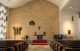 Interior view of a church with altar, pews and religious sculptures.