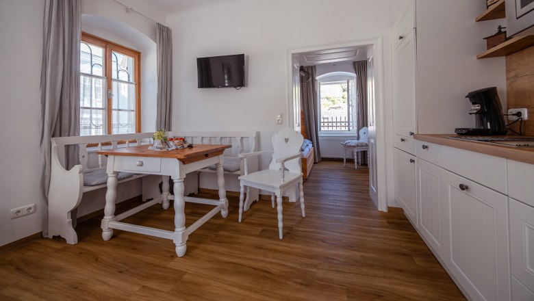 Bright, cozy room with wooden floor, dining table, chairs and kitchenette.