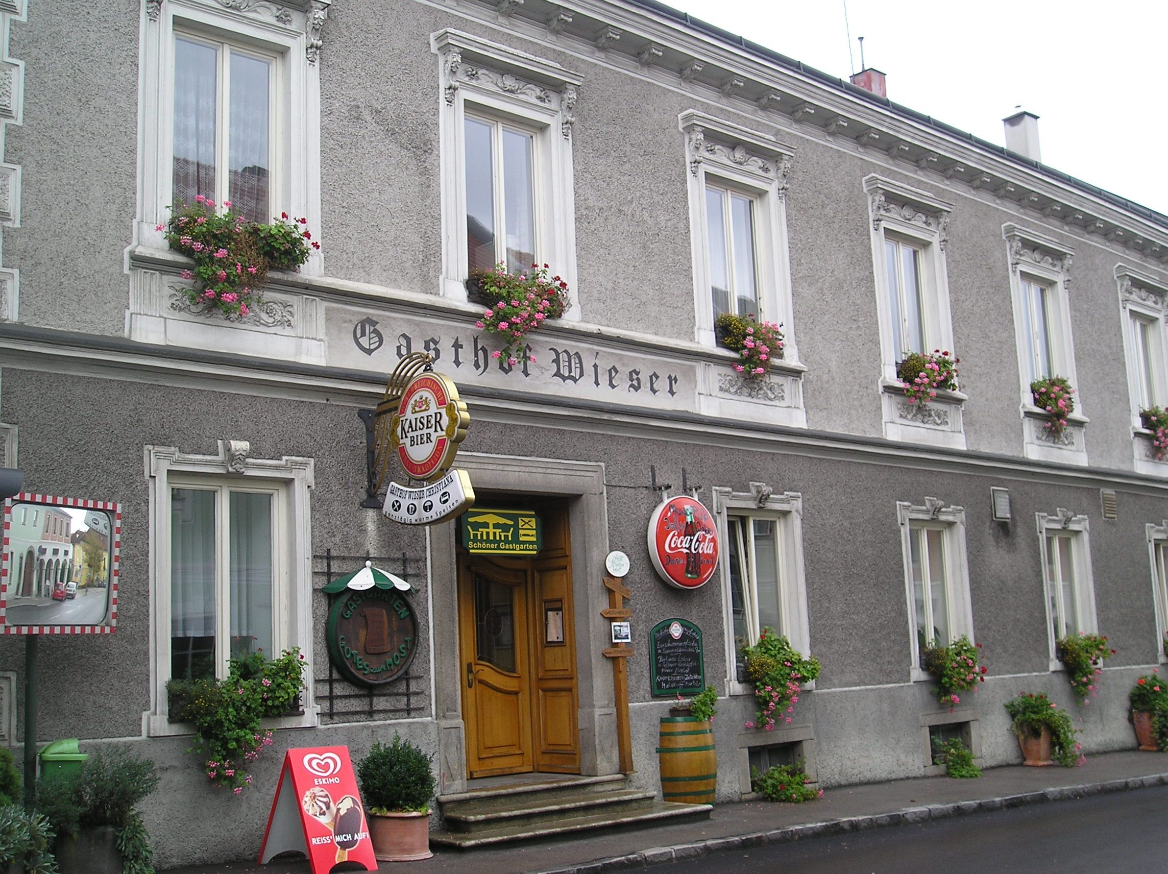 Facade of the Wieser inn with flower boxes and advertising signs.