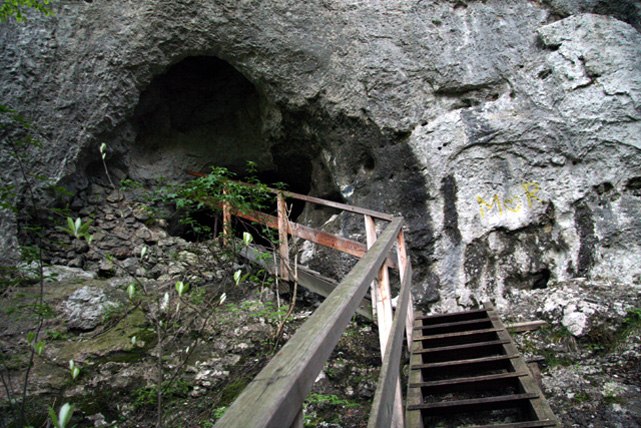 Entrance to a cave with wooden stairs and railings.
