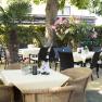A cozy outdoor area of a caf&eacute; with tables, chairs and plants.