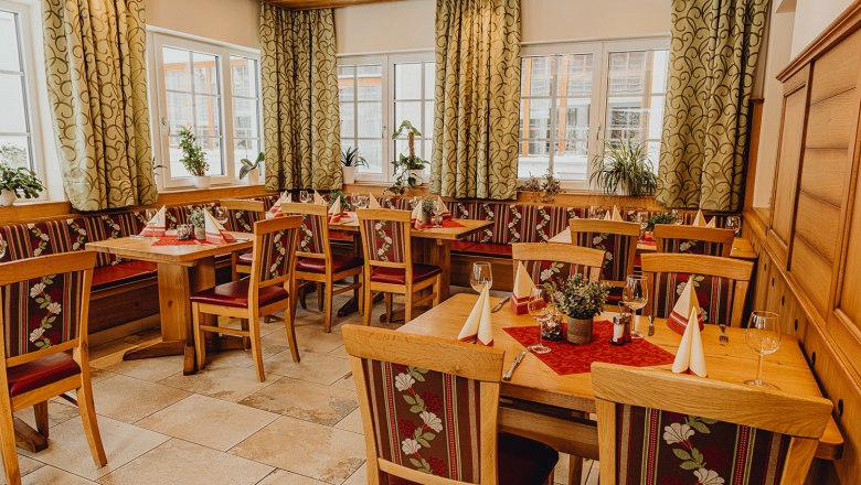 Cozy restaurant with wooden furniture, decorated tables and plants by the window.