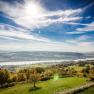 Panoramic view of a river landscape with green fields and blue sky.