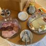 A breakfast buffet with cold cuts, cheese, vegetables, pastries and drinks on a table.