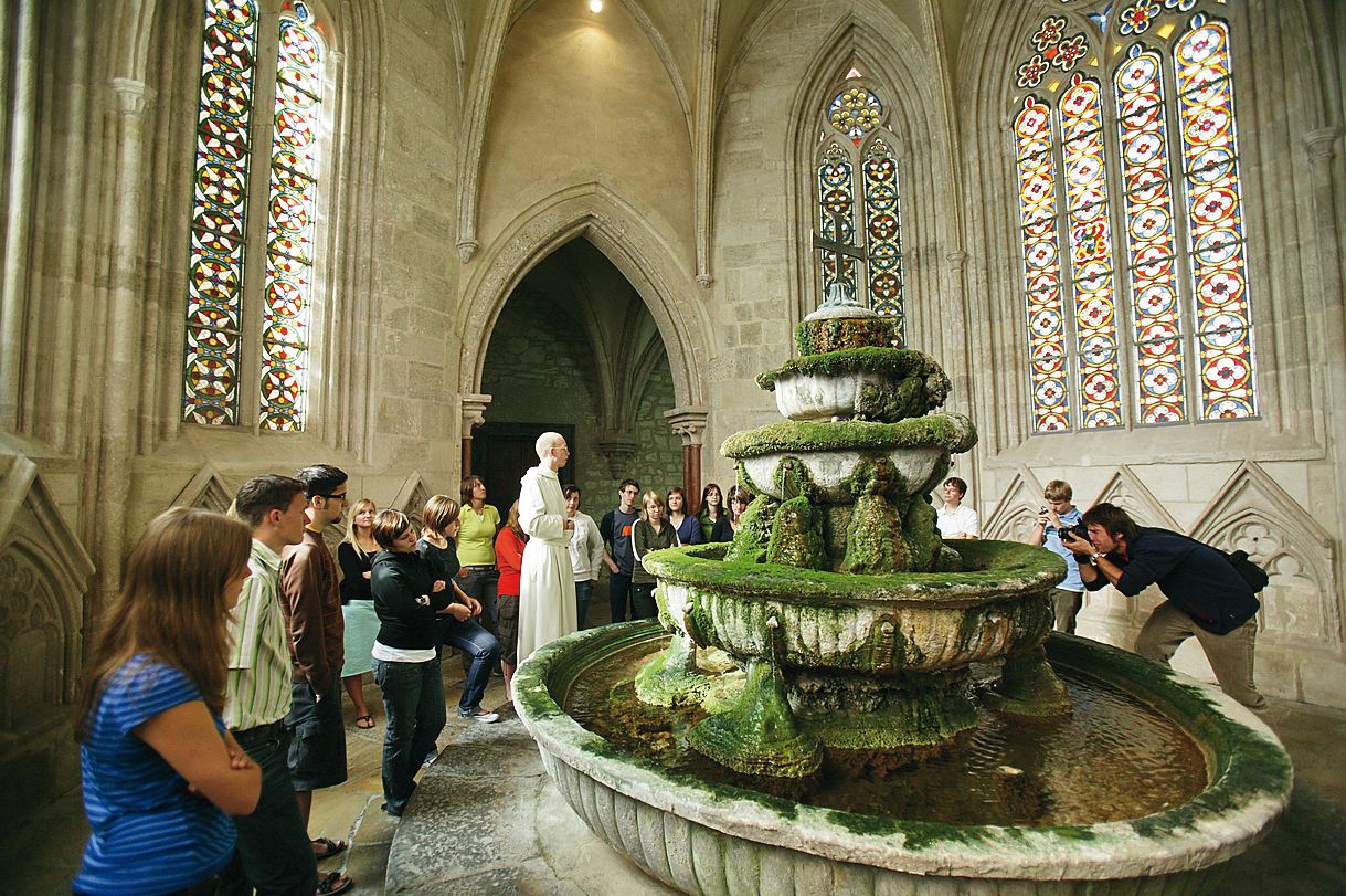 Interior view of the well house in Heiligenkreuz Abbey with visitors and a monk.