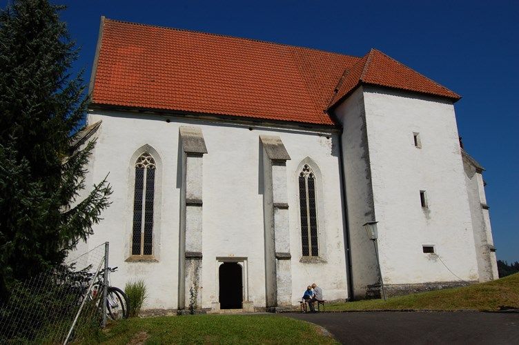 White church with a red roof and Gothic windows, blue sky.