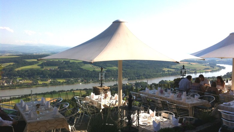 Terrace with tables and parasols, view of the river and countryside.