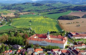 Aerial view of Seitenstetten Benedictine Abbey surrounded by green fields and hills.