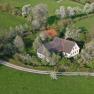 Aerial view of a farm surrounded by blossoming trees and green meadows.